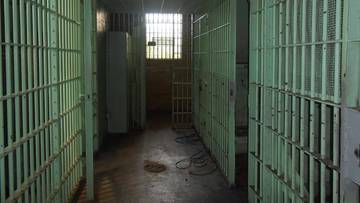 Korytarz więzienny z celami po obu stronach, z oknem na końcu korytarza.