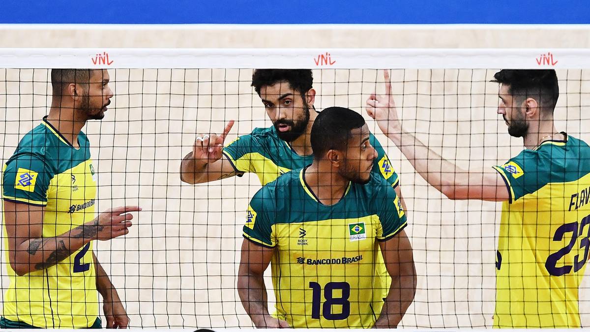 Siatkarze w ż&oacute;łto-zielonych strojach z numerami na plecach stoją przy siatce.