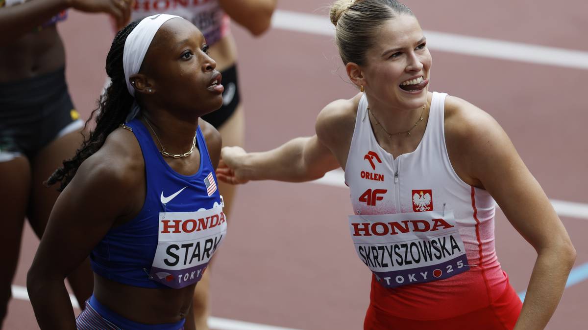 Dwie sportsmenki biegną obok siebie podczas zawodów lekkoatletycznych. Jedna z nich, ubrana w niebieski strój sportowy, ma na imię "STARK" widoczne na koszulce. Druga zawodniczka, w czerwono-białym stroju z napisem "SKRZYżOWSKA" i "TOKYO 2020", patrzy w bok zdeterminowana.