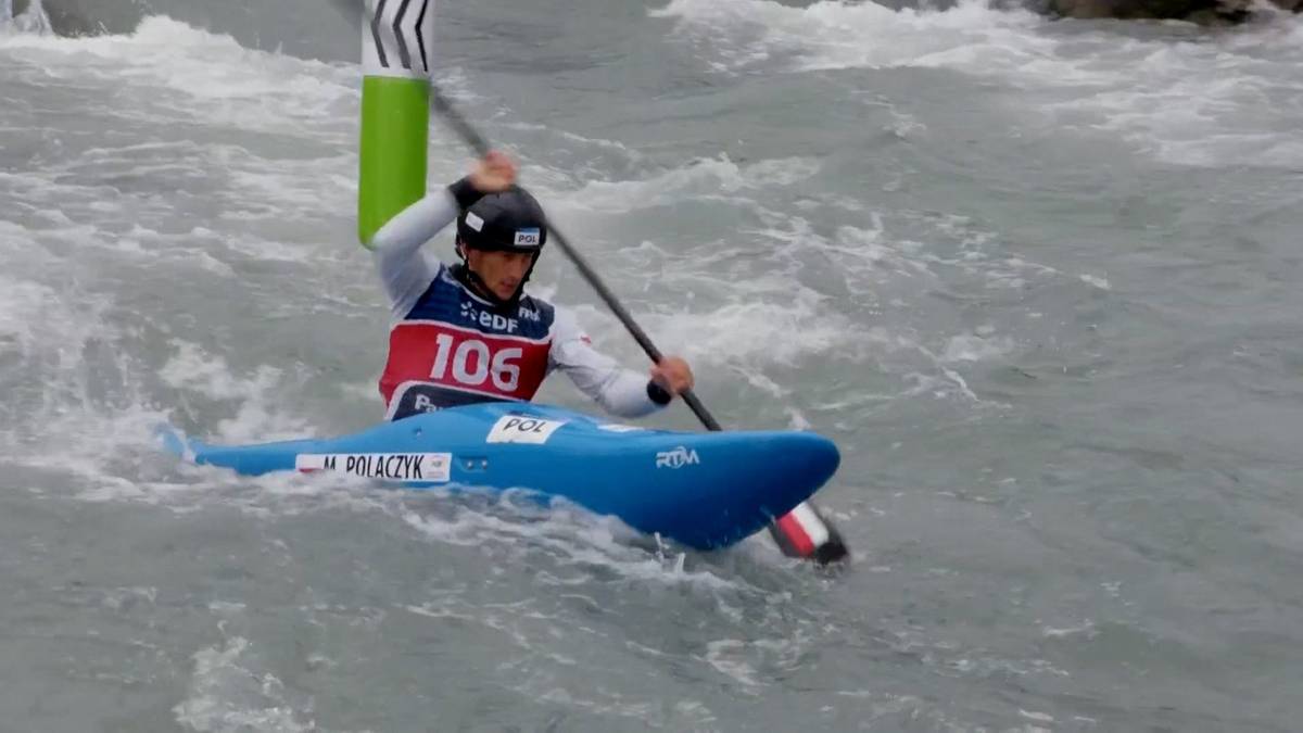 Sportowiec w niebieskim kajaku płynie po wzburzonej wodzie, trzymając wiosło.