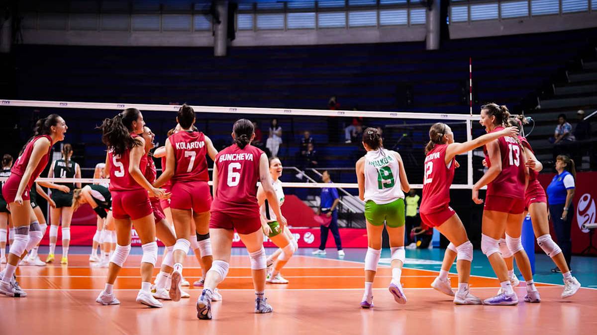 Siatkarki w czerwonych i białych strojach grają mecz siatkówki, jedna z zawodniczek w zielonym stroju przygotowuje się do podania.