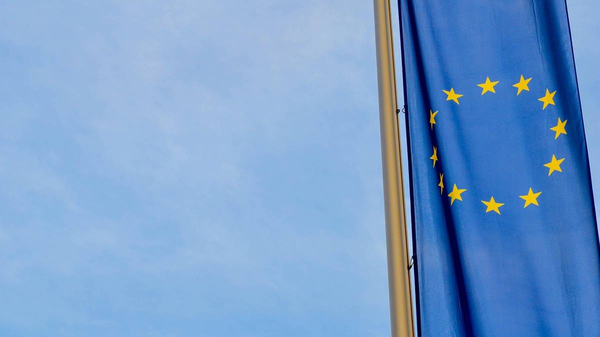 Niebieska flaga Unii Europejskiej z żółtymi gwiazdami na tle błękitnego nieba.