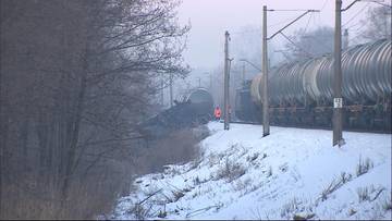 Wykolejony pociąg towarowy złożony z cystern przewożących olej napędowy, stojący na zasypanych śniegiem torach kolejowych.