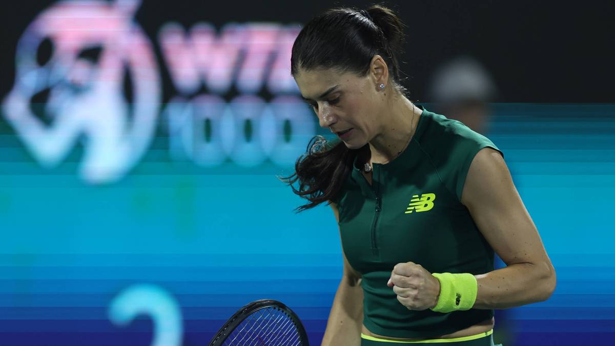 Rumuńska tenisistka w zielonym stroju sportowym z żółtą opaską na nadgarstku, grająca w tenisa.