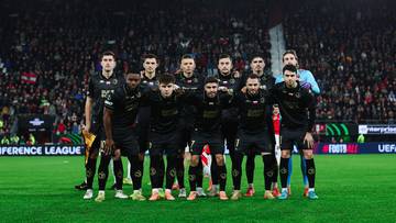 Drużyna piłkarska pozuje do zdjęcia na boisku piłkarskim.