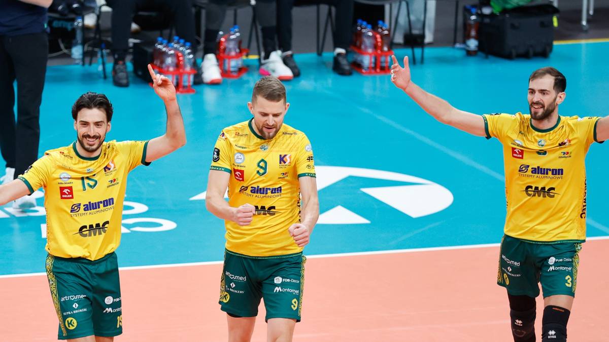 Trzech siatkarzy w ż&oacute;łtych koszulkach sportowych z zielonymi elementami, radośnie unoszących ręce.