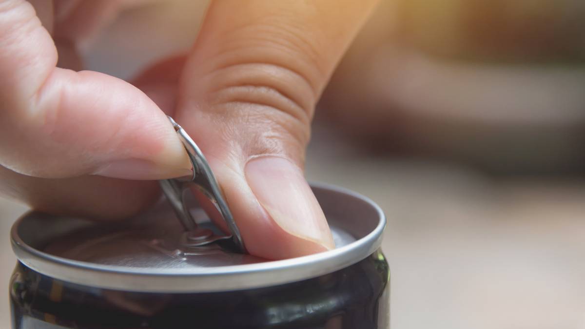 Dłoń otwierająca puszkę napoju.