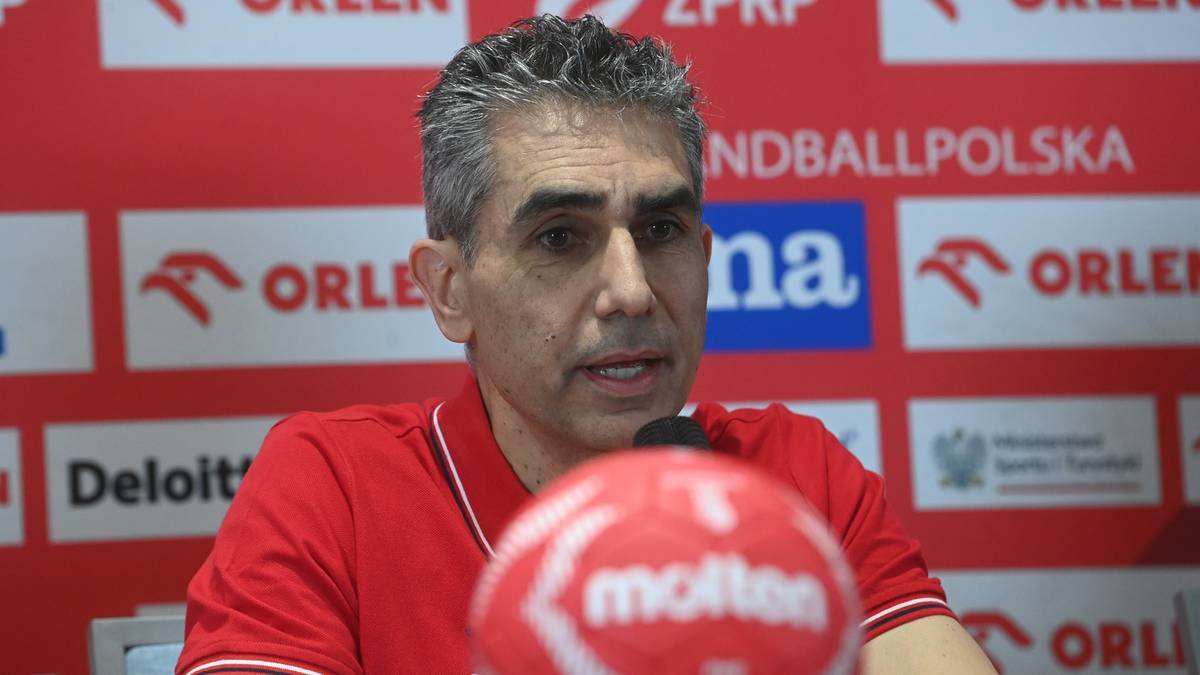 Trener reprezentacji Polski w piłce ręcznej przemawia do mikrofonu podczas konferencji prasowej.