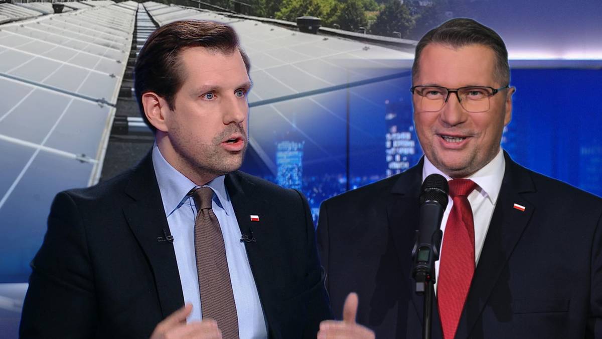 Dw&oacute;ch mężczyzn w garniturach stoi przed ekranem z widokiem na panele fotowoltaiczne.