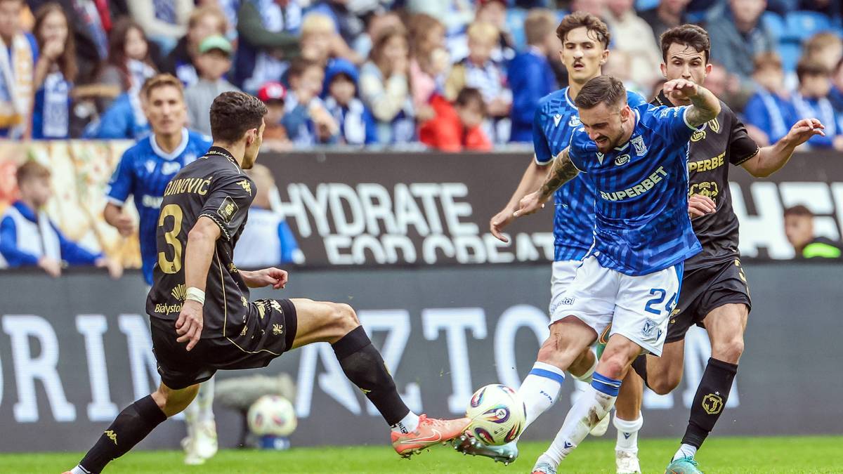 Piłkarze walczący o piłkę na boisku podczas meczu piłki nożnej.