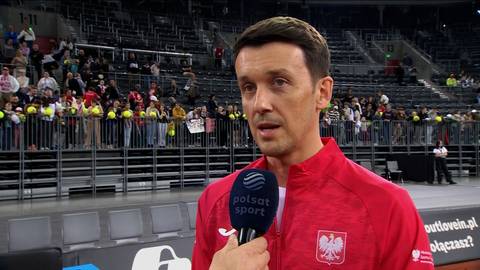 Mężczyzna w czerwonej bluzie z orłem na piersi wypowiada się do mikrofonu Polsat Sport. W tle widoczne są trybuny wypełnione widzami.