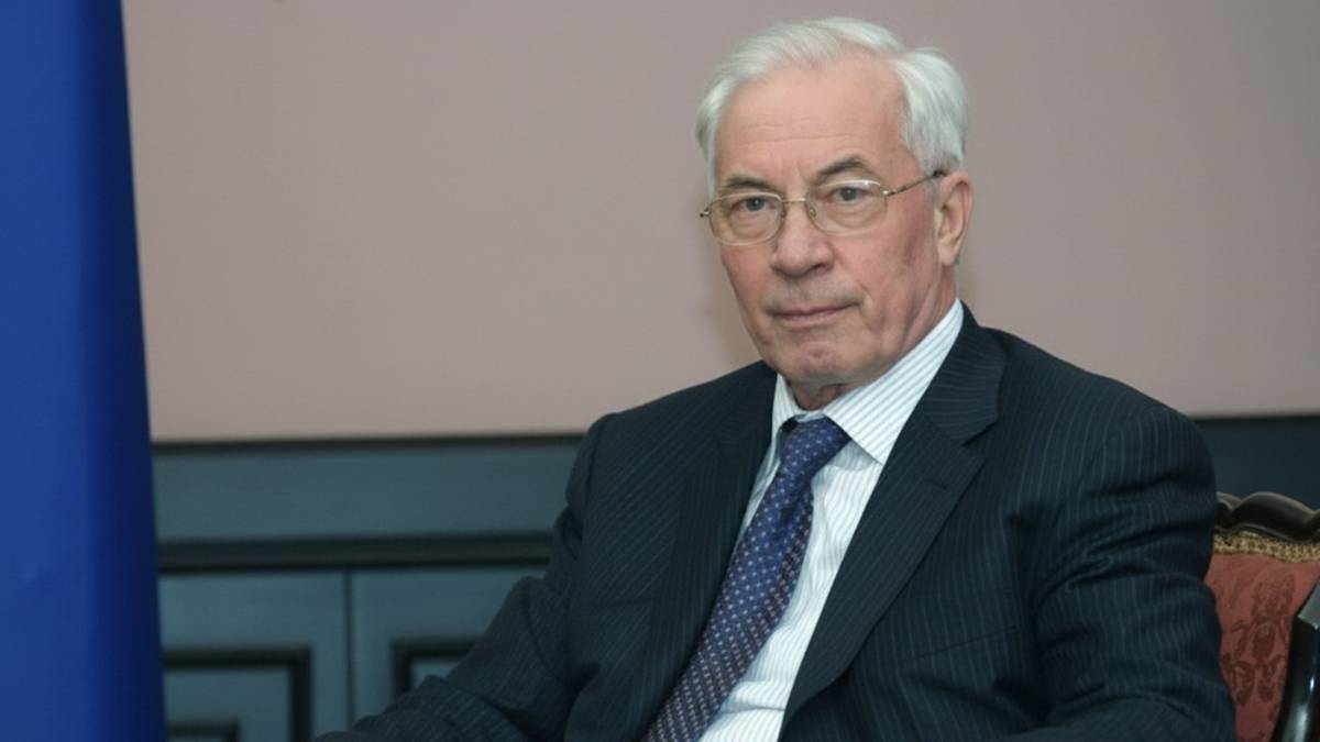 Portret starszego mężczyzny w garniturze i krawacie, siedzącego i patrzącego w obiektyw.