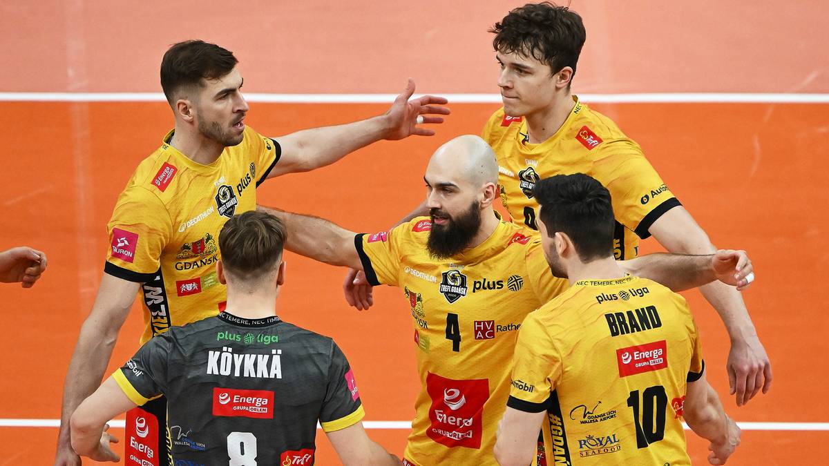 Siatkarze w żółtych strojach celebrują zdobyty punkt, jeden z nich jest w szarym stroju.