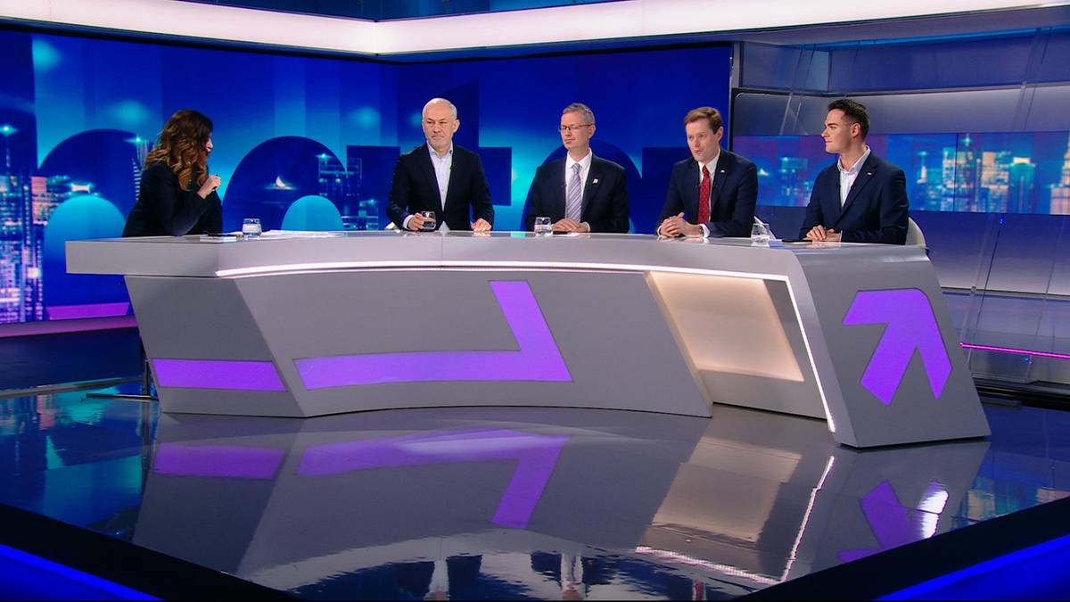 Pięć os&oacute;b siedzi przy stole w studiu telewizyjnym, dyskutując.