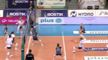 Graczki w białych strojach pr&oacute;bują zablokować atak przeciwniczek w meczu siatk&oacute;wki.