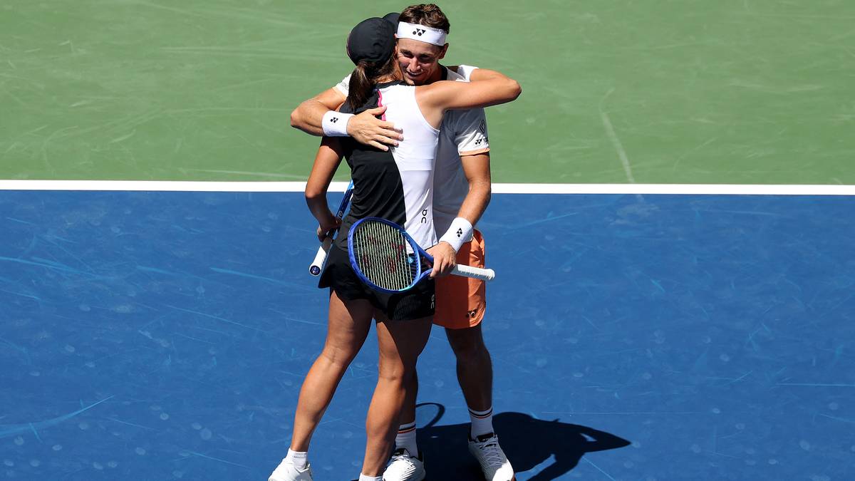 Iga Świątek i jej partner przytulają się na korcie tenisowym po zwycięskim meczu.