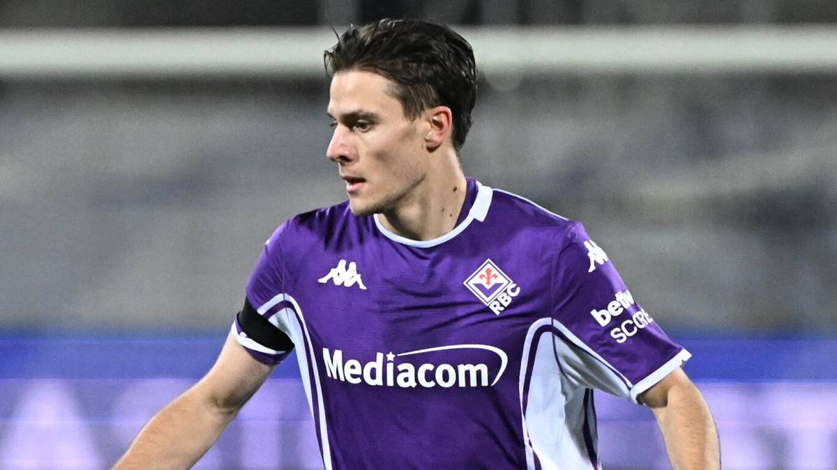 Piłkarz Fiorentiny prowadzi piłkę na boisku.