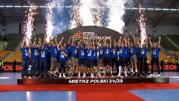 Drużyna piłkarzy ręcznych w niebieskich strojach stoi na podium, świętując zwycięstwo. W tle widać tablicę z napisem "MISTRZ POLSKI 24/25", a nad głowami zawodnik&oacute;w unoszą się fontanny fajerwerk&oacute;w. Na trybunach siedzą kibice.