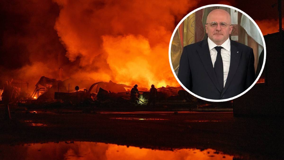 Nocny widok Kijowa z płonącymi budynkami i dymem unoszącym się w powietrzu, z portretem mężczyzny w garniturze w prawym g&oacute;rnym rogu.