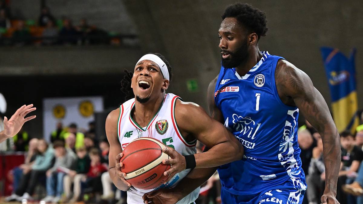 Koszykarz w białej koszulce prowadzi piłkę, ścigany przez rywala w niebieskim stroju.