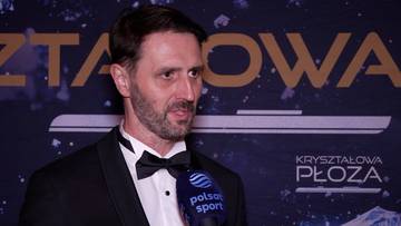 Mężczyzna w czarnym smokingu z muszką, wypowiada się do mikrofonu.