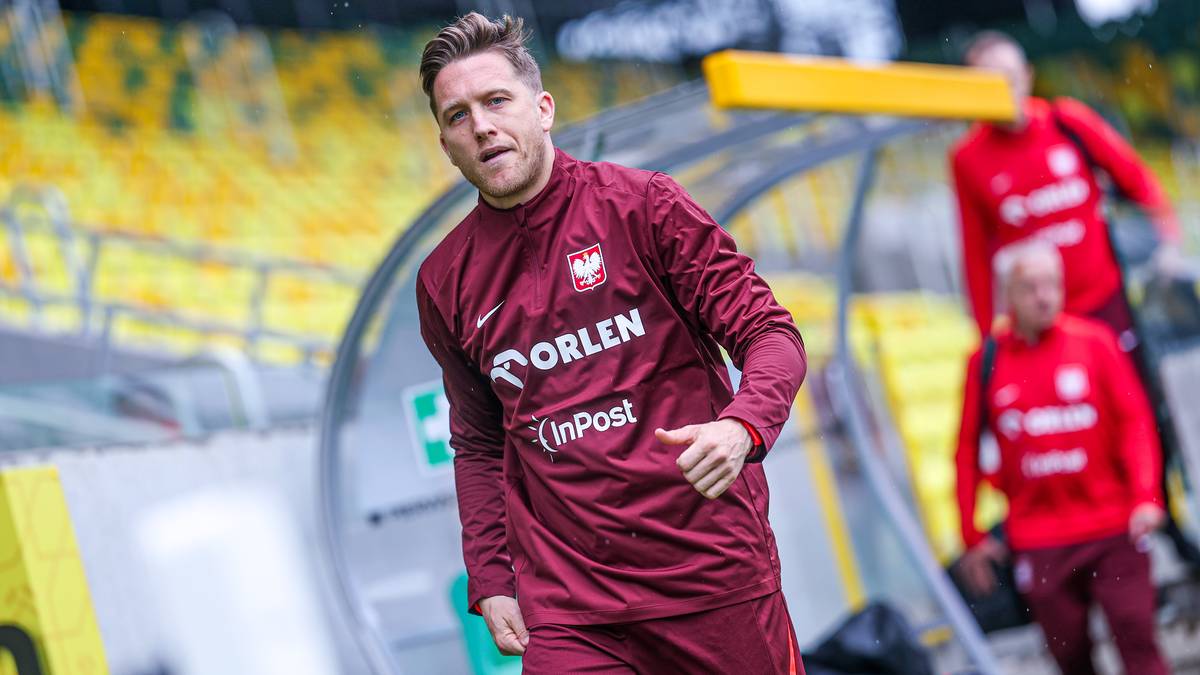 Piłkarz w bordowej koszulce reprezentacji Polski z białym orłem na piersi, wychodzi ze stadionu.