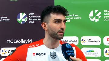 Portret siatkarza Marcina Janusza podczas wywiadu, z mikrofonem przed nim. Tło stanowi grafika z logotypami CEV Champions League.