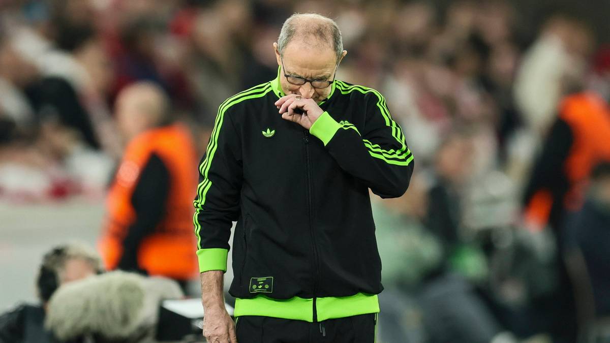 Mężczyzna w czarnej sportowej kurtce z zielonymi pasami trzymający się za nos.