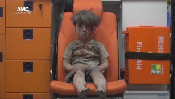 Zakrwawiony, pokryty kurzem chłopiec wyciągnięty z gruzów. Przeżył bombardowanie w Aleppo