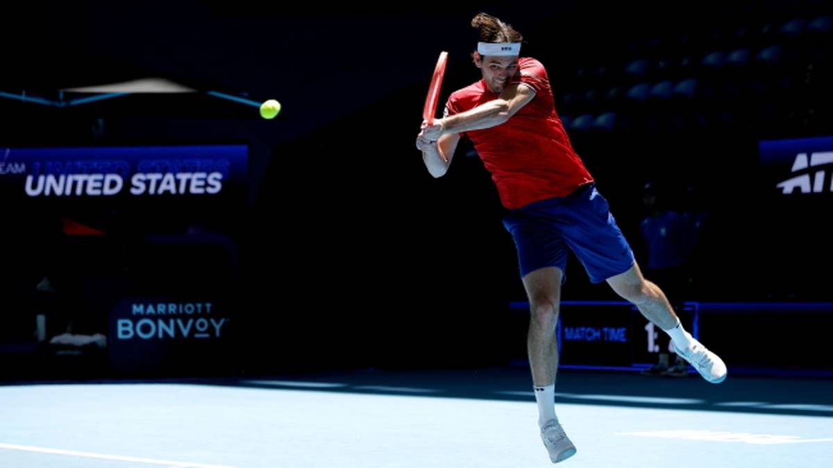 Tenisista w akcji, wykonujący uderzenie na korcie tenisowym.