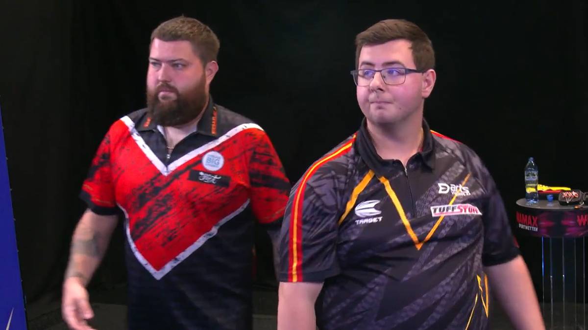 Dw&oacute;ch mężczyzn w koszulkach sportowych stoi obok siebie, patrząc w prawą stronę.