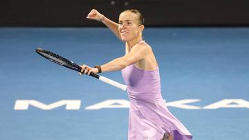 Tenisistka w fioletowej sukience świętuje punkt, trzymając rakietę tenisową.