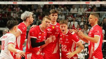 Siatkarze reprezentacji Polski w czerwonych strojach pozują do zdjęcia, świętując akcję meczową.