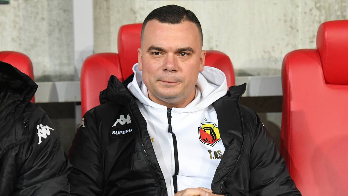 Mężczyzna siedzi na ławce rezerwowych w stroju sportowym.