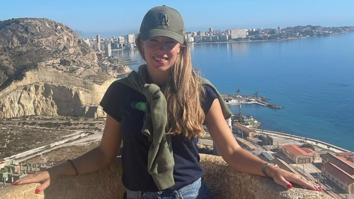 Magdalena Fręch, tenisistka, w czapce i koszulce, z widokiem na miasto i morze w tle.