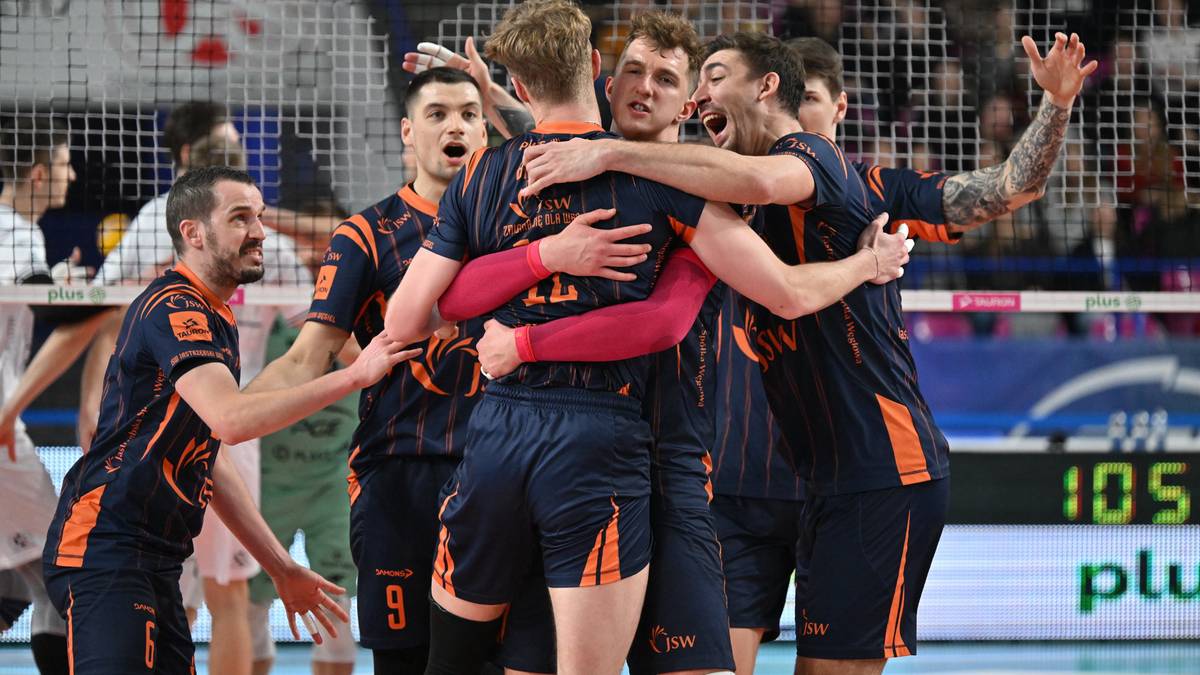 Siatkarze Jastrzębskiego Węgla świętują zwycięstwo, przytulając się na boisku po meczu.