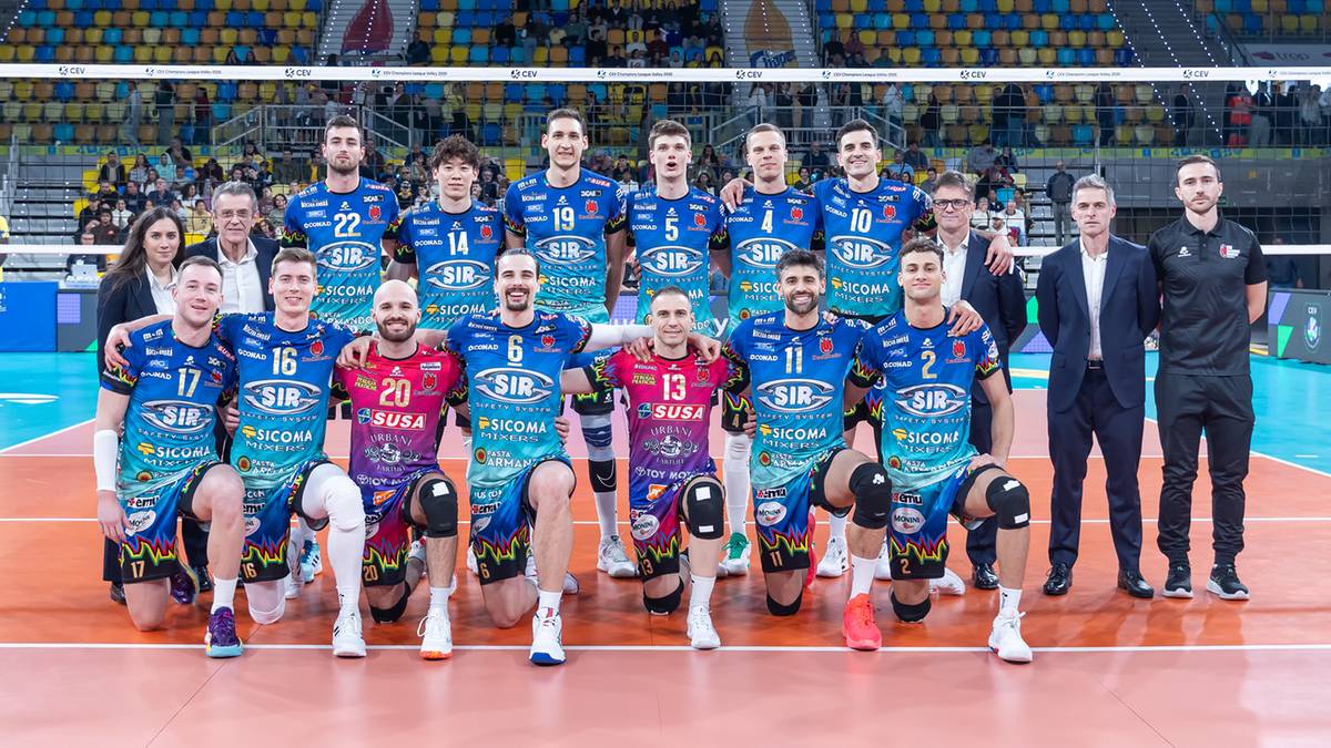 Drużyna siatkarzy Sir Susa Scai Perugia w strojach meczowych na tle trybun hali sportowej.