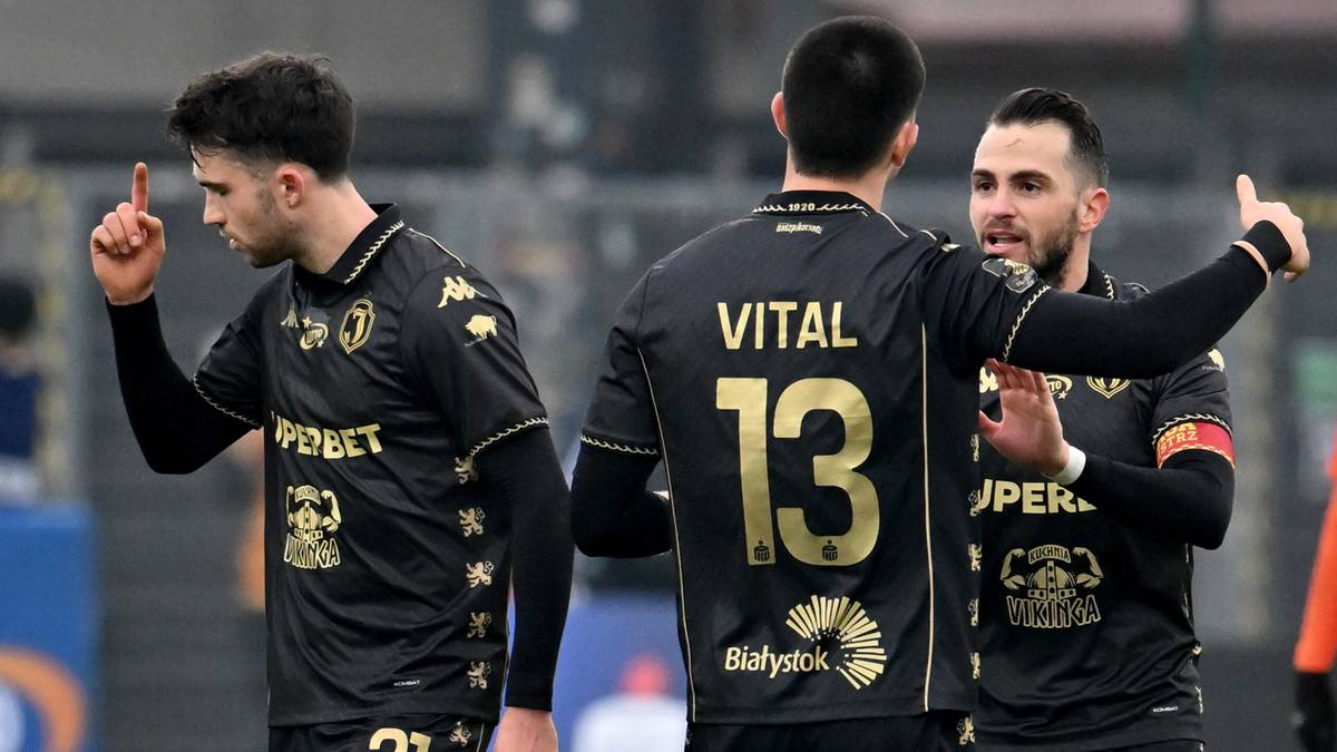 Piłkarze w czarnych strojach świętują zdobycie bramki, jeden z nich podnosi palec wskazujący do góry.