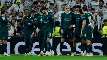 Piłkarze Manchesteru City w zielonych strojach świętują na boisku, z trybunami kibiców w tle.