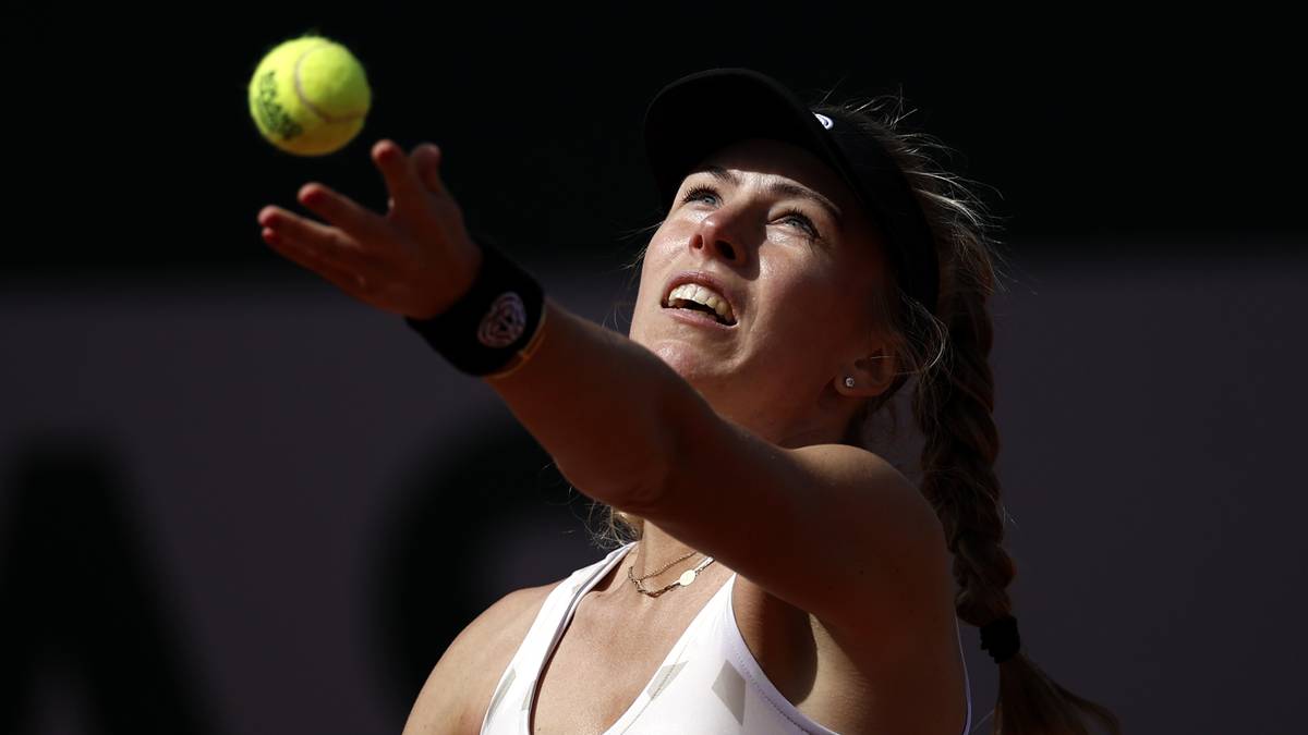 Tenisistka podczas serwisu, z piłką tenisową w dłoni i z wzrokiem skierowanym w górę.