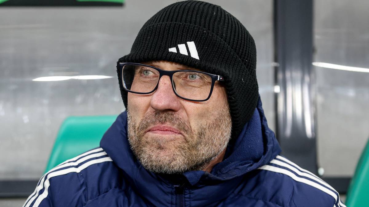 Marek Papszun w czapce i kurtce sportowej siedzi na ławce.