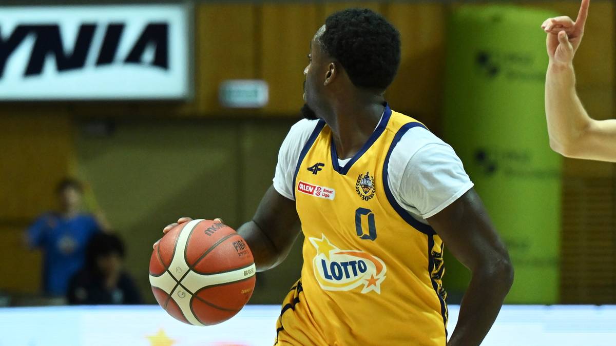 Koszykarz w żółtej koszulce z numerem 0 i logo Lotto, prowadzący piłkę w trakcie meczu.