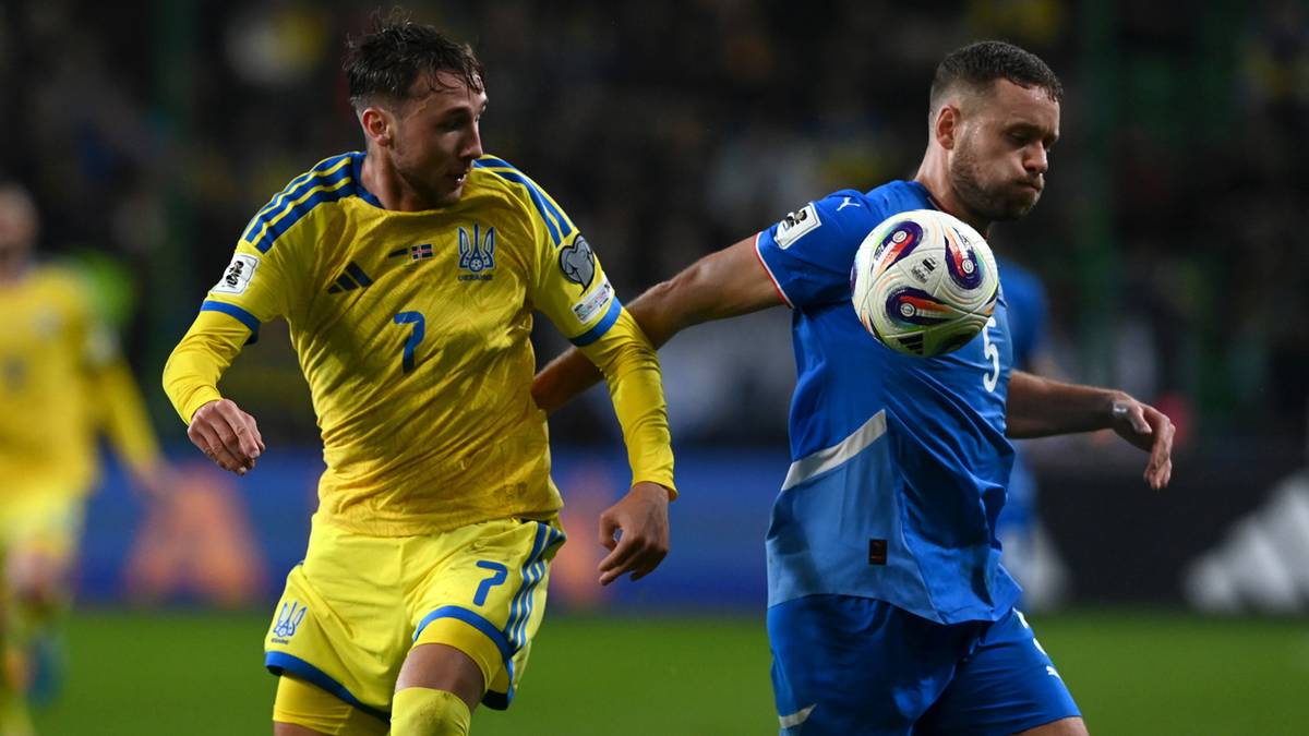 Dwóch piłkarzy w akcji podczas meczu piłki nożnej, jeden w żółtej koszulce z numerem 7, drugi w niebieskiej koszulce.