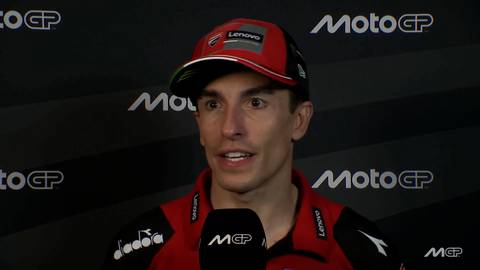 Marc M&aacute;rquez, ubrany w czerwono-czarną kurtkę wyścigową i czapkę z daszkiem z logo Lenovo, patrzy w stronę obiektywu i m&oacute;wi do mikrofonu z logo MotoGP.