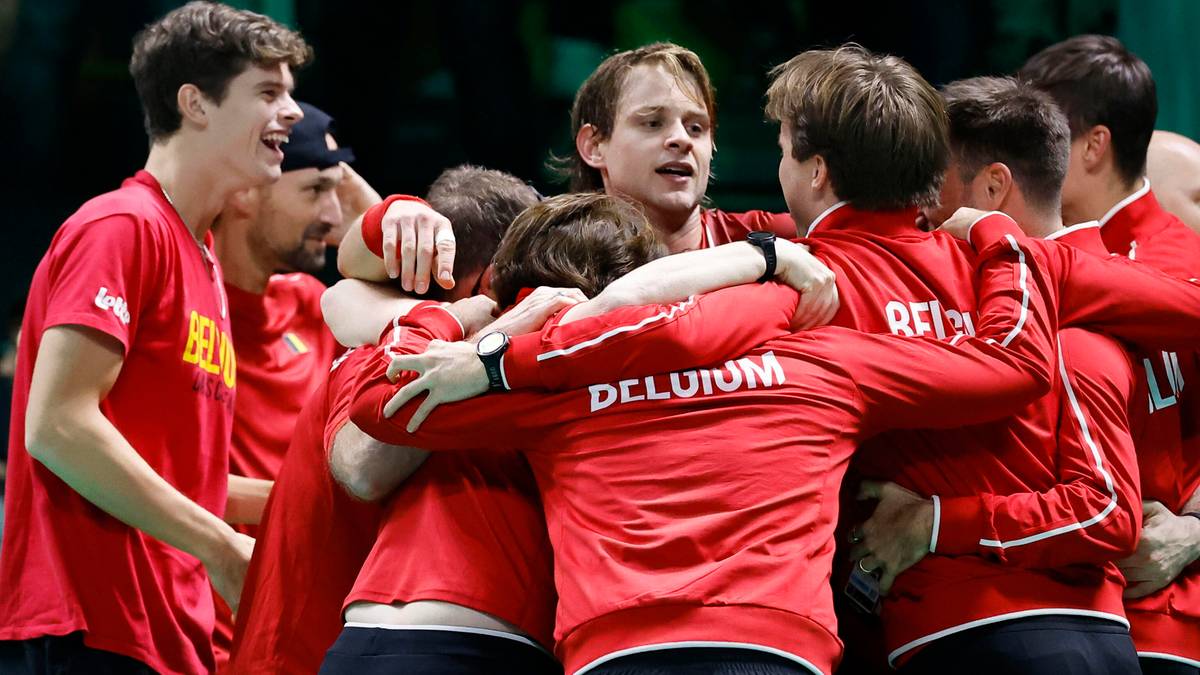 Grupa tenisistów w czerwonych strojach świętuje zwycięstwo, przytulając się.