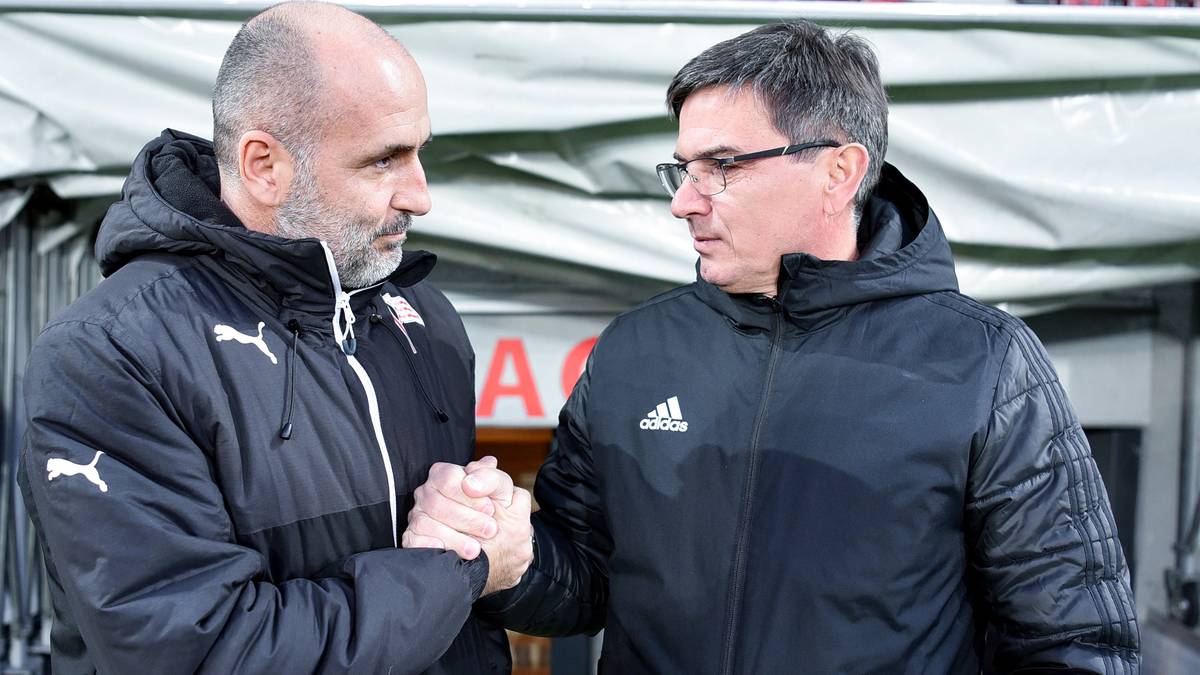 Dwóch mężczyzn w kurtkach sportowych ściska sobie dłonie, patrząc na siebie z uwagą.