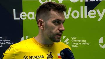 Portret siatkarza Marcina Komendy w ż&oacute;łtej koszulce, udzielającego wywiadu. W tle zielony baner z logotypami rozgrywek siatkarskich.