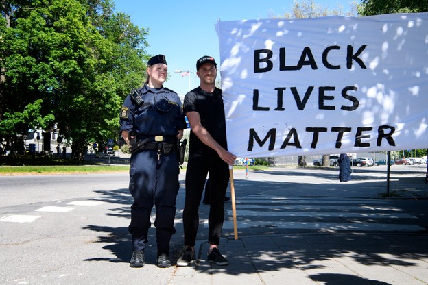 Szwedzcy policjanci trzymają transparent z napisem 