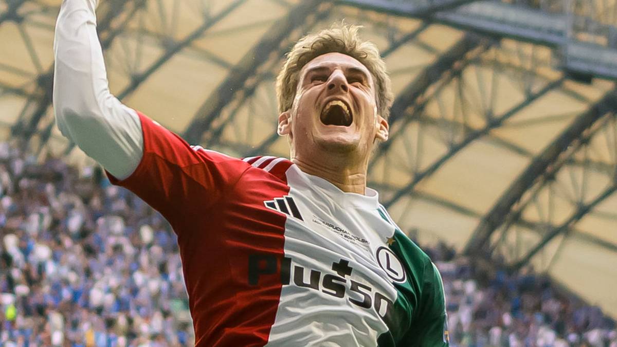 Piłkarz w koszulce GKS Katowice z uniesioną prawą ręką i otwartymi ustami, wyrażający radość.