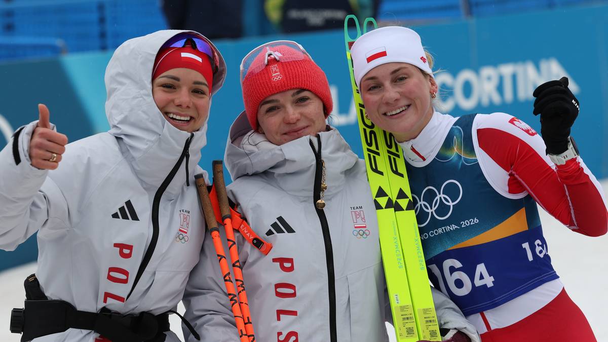 Trzy zawodniczki z Polski w strojach narciarskich pozują do zdjęcia, dwie z nich trzymają narty i kijki, jedna pokazuje kciuk w g&oacute;rę.